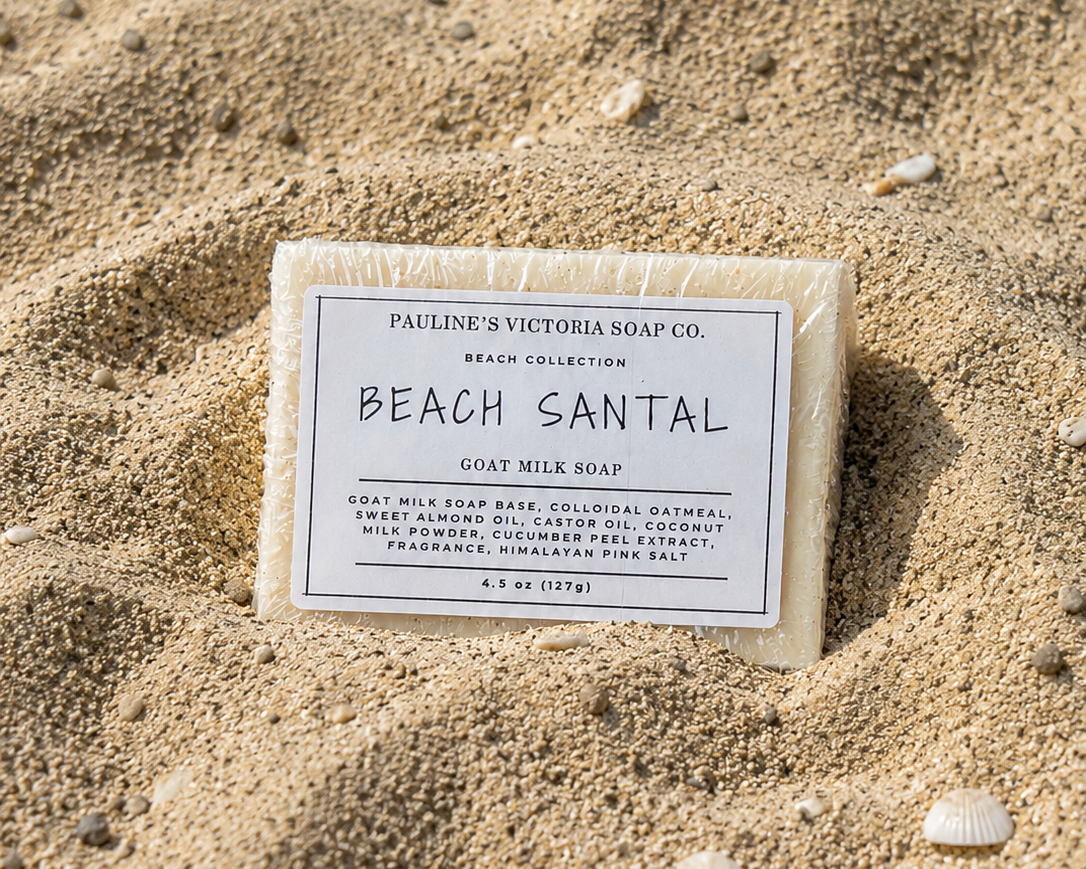 Bar of soap labeled 'Beach Santal' from Pauline's Victoria Soap Co. on a sandy background