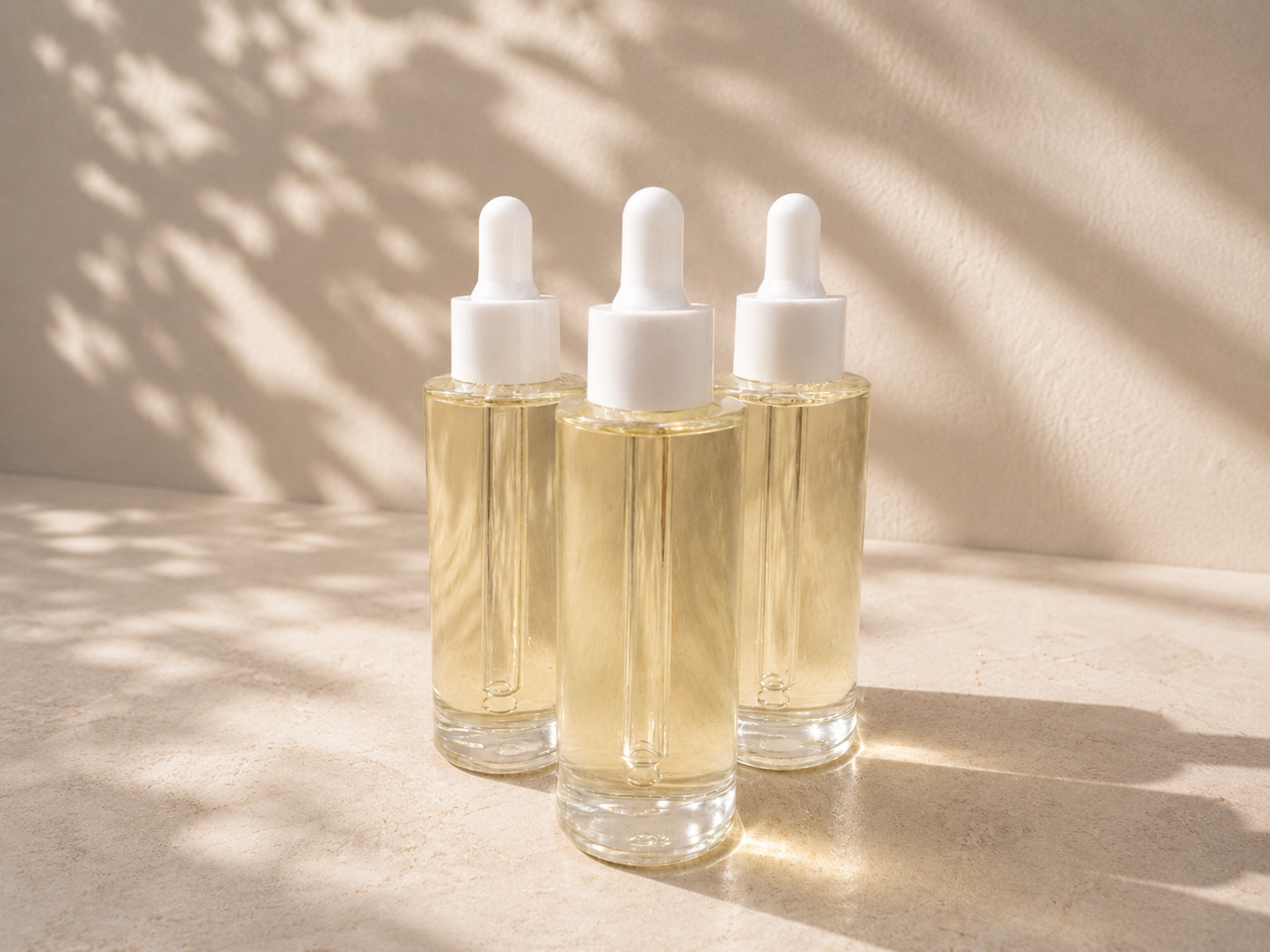 Three dropper bottles with a clear liquid on a beige surface with shadows.