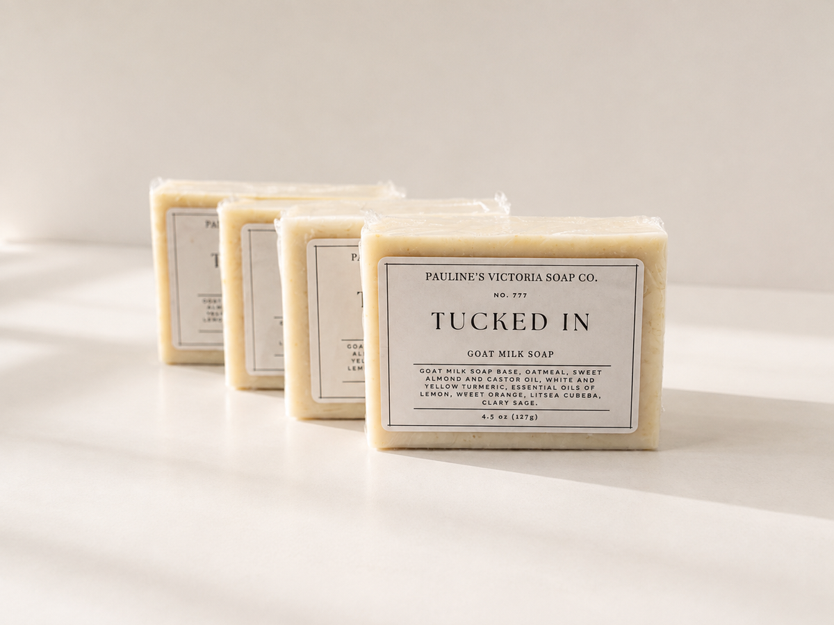 Four rectangular bars of soap arranged in a row on a white surface, with the front bar labeled 'PAULINE'S VICTORIA SOAP CO. TUCKED IN GOAT MILK SOAP.