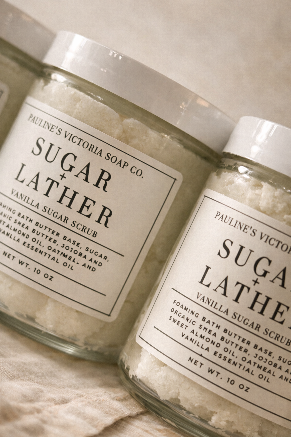 Two jars of Pauline's Victoria Soap Co. Vanilla Sugar Scrub on a textured surface.