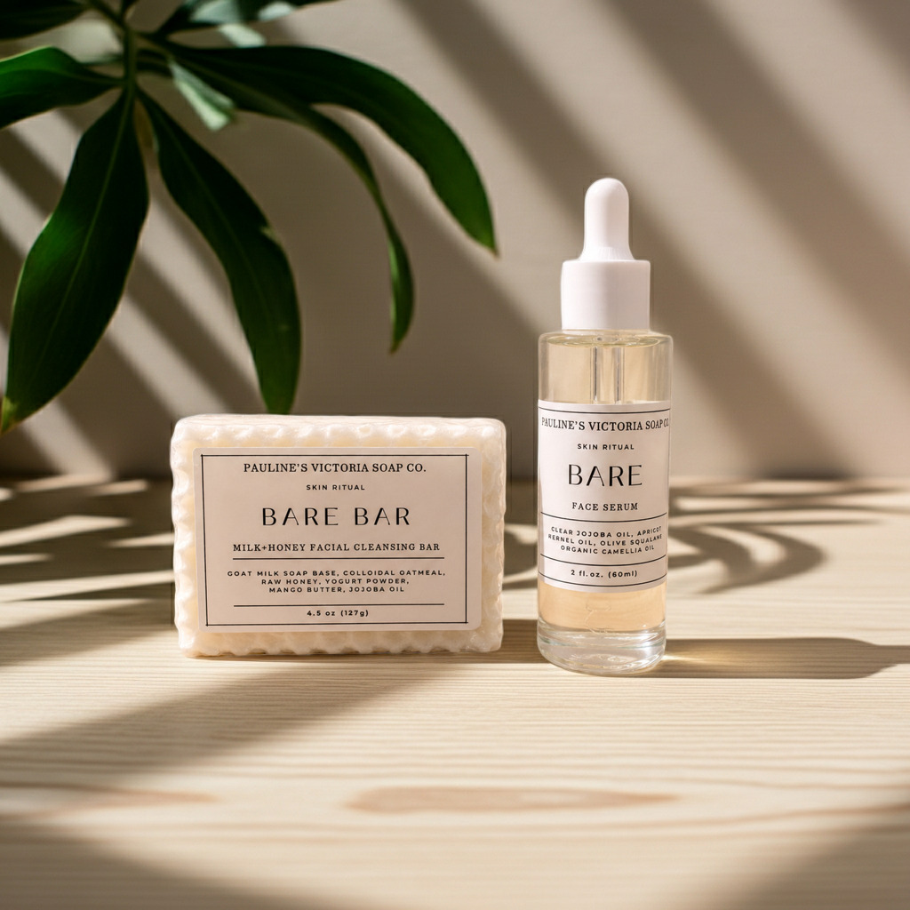 A skincare set from Pauline's Victoria Soap Co. featuring a rectangular Milk-Honey Facial Cleansing Bar and a clear dropper bottle of Bare Face Serum, styled on a light wood surface with leaf shadows.